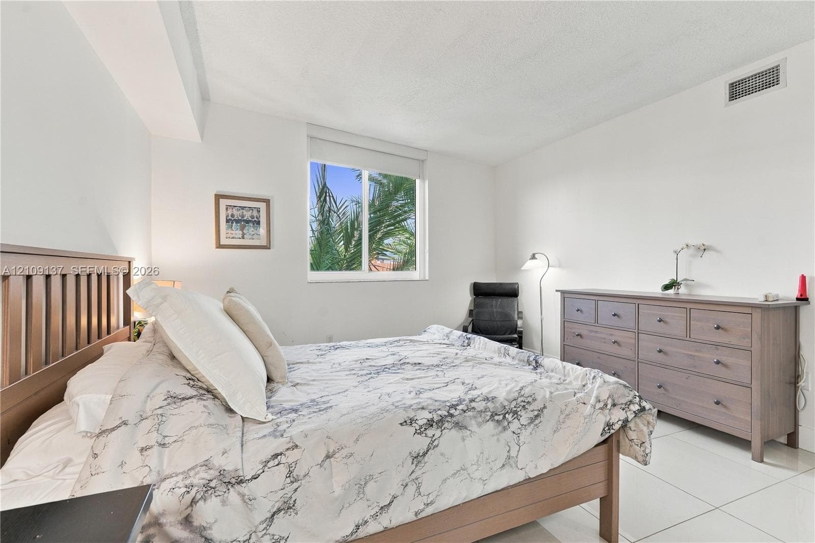Spacious room featuring neutral wall tones, large-format tile flooring, and a single-pane sliding window