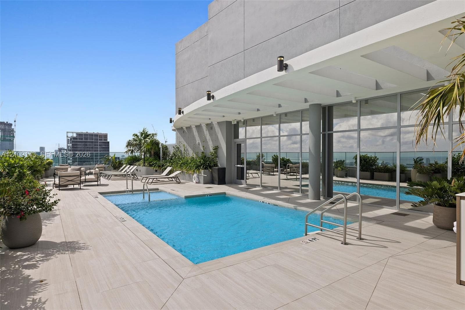 Rooftop terrace featuring an inground pool with built-in lounge ledge, expansive light-toned tile decking, integrated structural pergola, and floor-to-ceiling glass wall panels