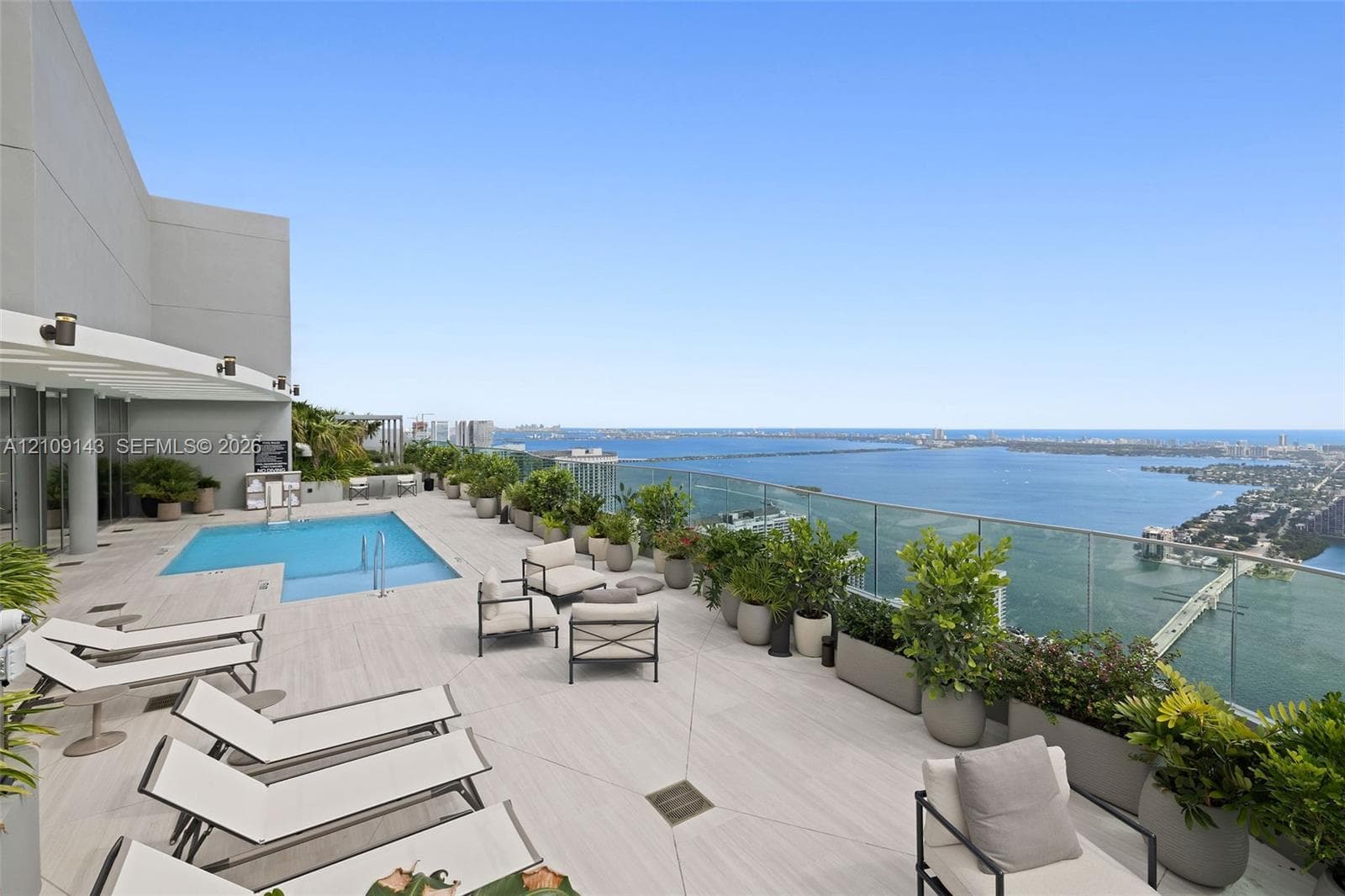 Rooftop terrace featuring an elevated swimming pool, glass panel railing, and light-toned tile flooring