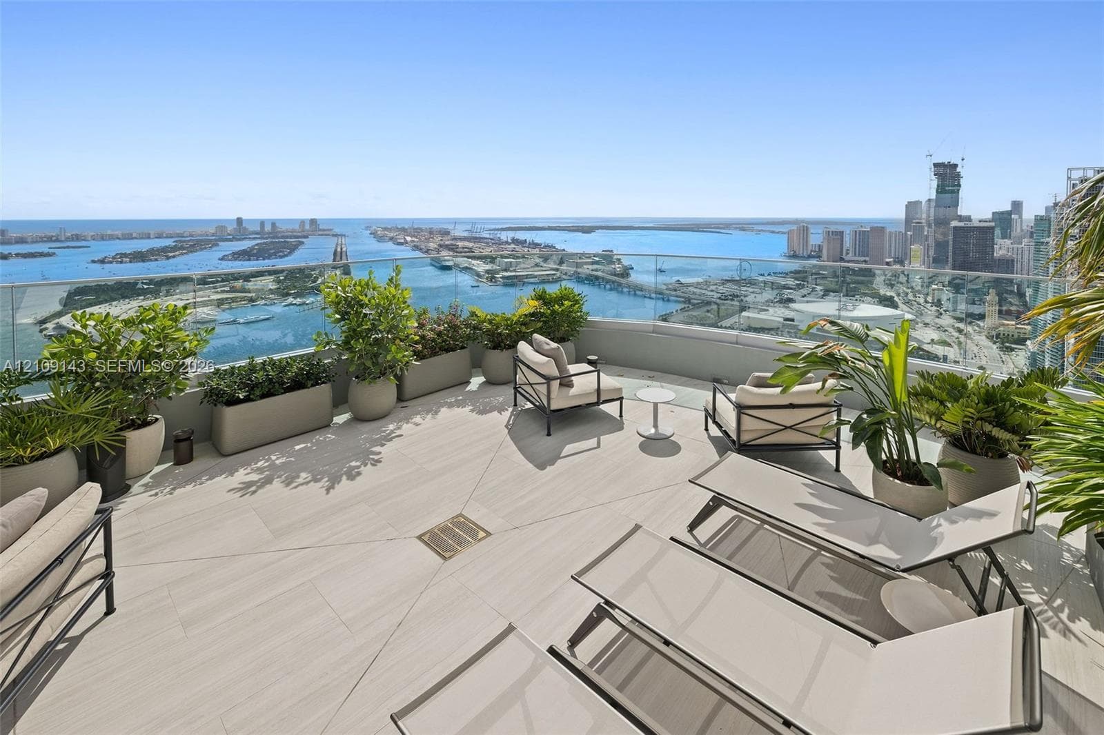 Expansive terrace featuring large-format porcelain tile flooring and a transparent glass railing overlooking the coastal skyline and harbor