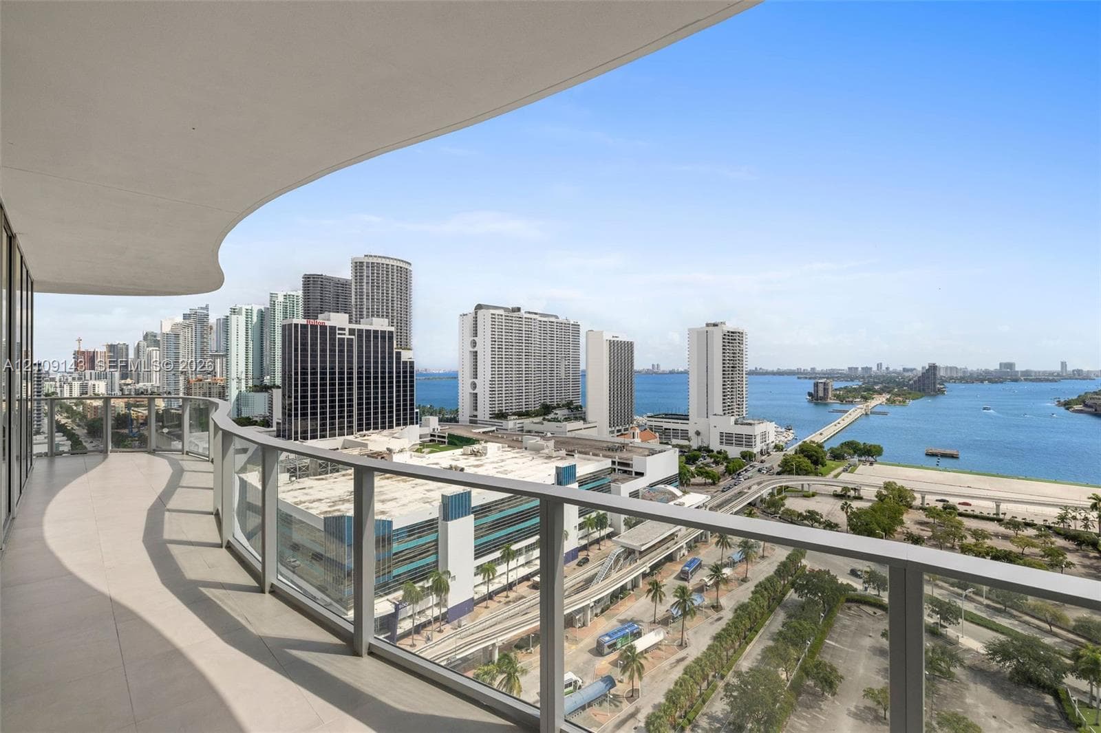 Expansive curved balcony featuring large-format tile flooring and glass panel railings