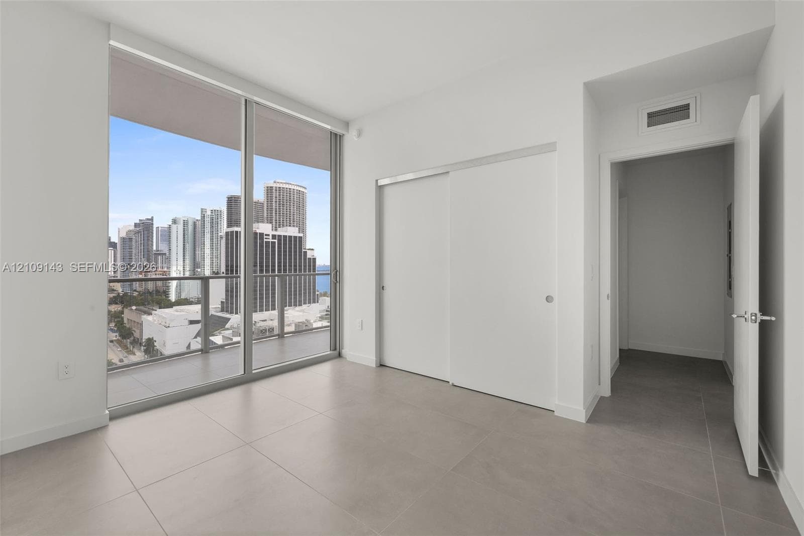 Floor-to-ceiling glass windows, private balcony, large format tile flooring, and built-in sliding door closet