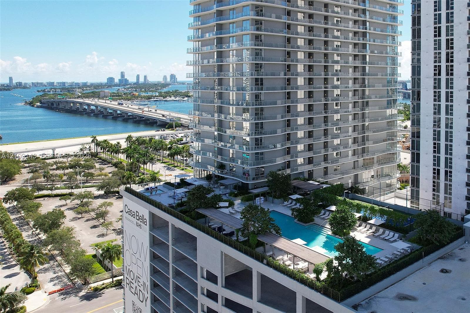 High-rise residential exterior featuring an elevated deck with a swimming pool, integrated landscaping, and covered lounge structures