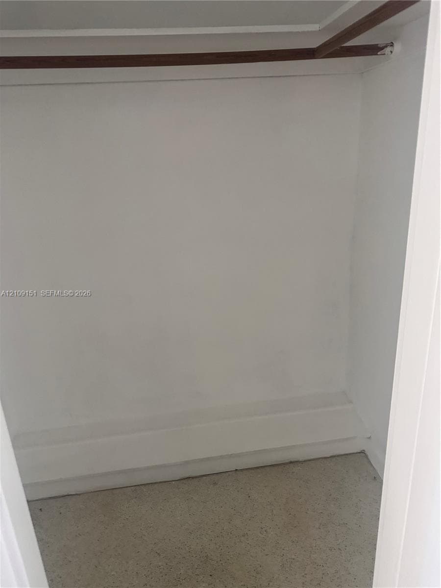 Storage closet featuring a wood-finish hanging rod and built-in shelving