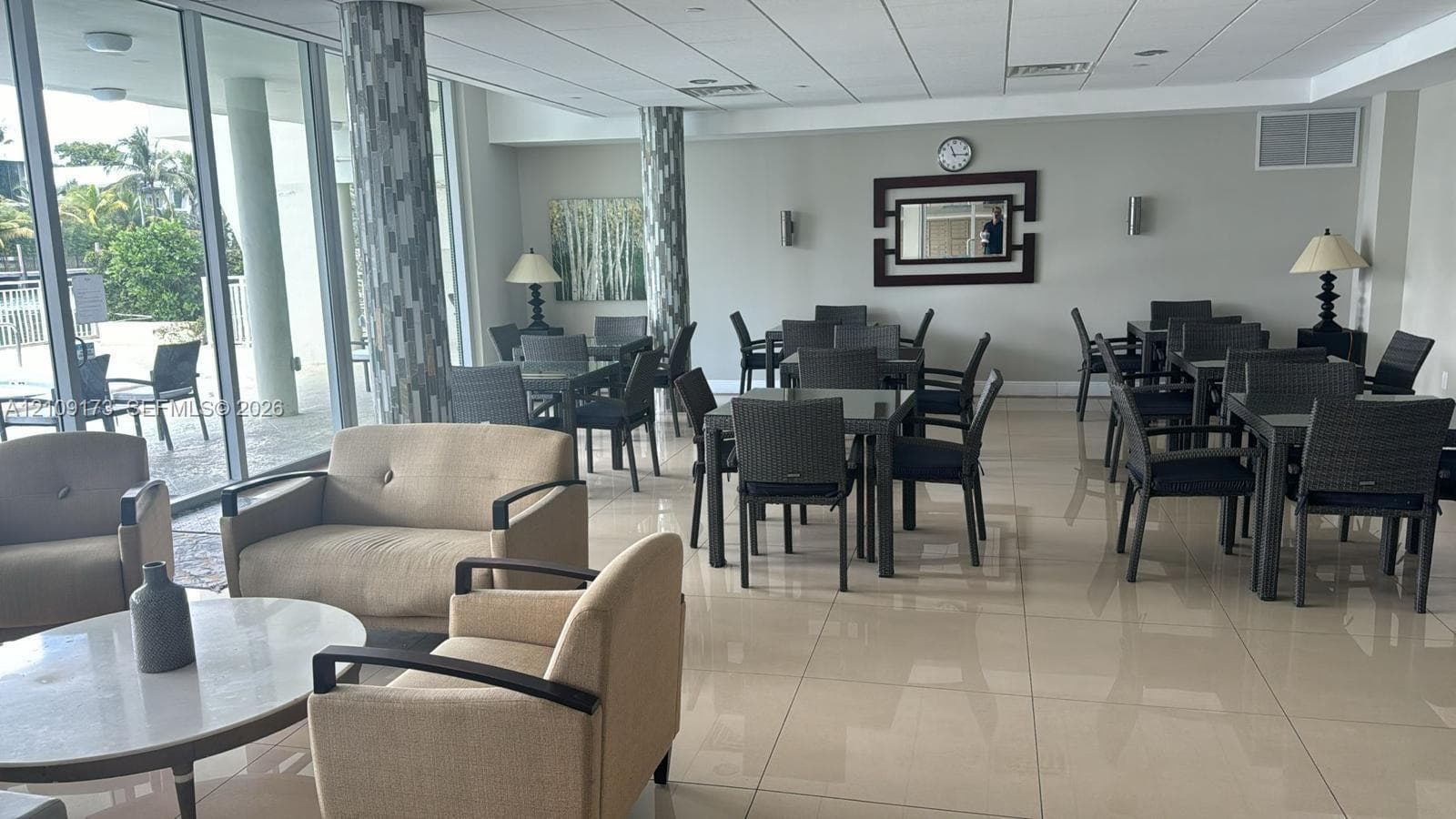Common area featuring floor-to-ceiling windows, polished tile flooring, decorative structural columns, and recessed lighting