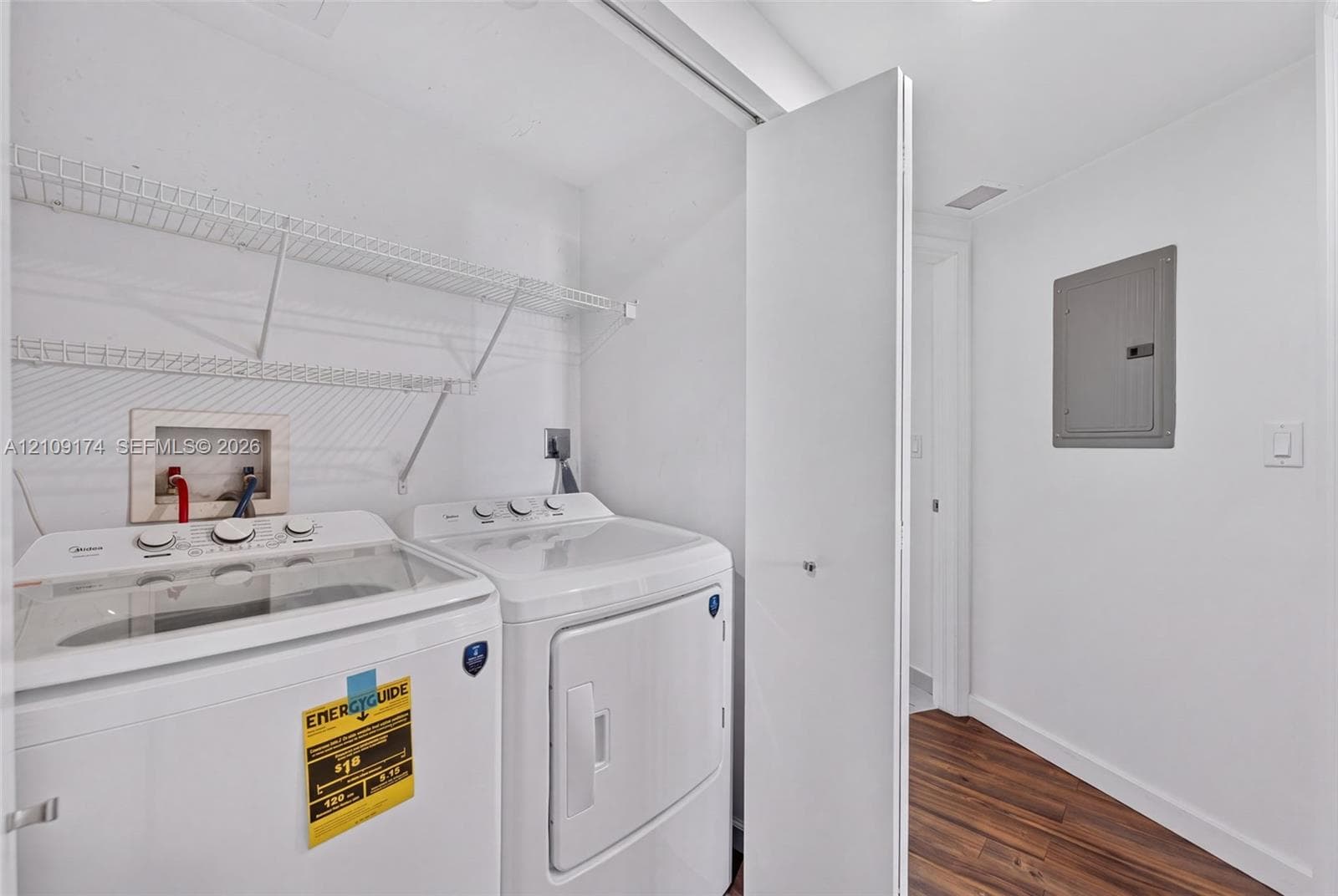 Laundry space featuring wood-finish flooring, white walls, and built-in white wire shelving