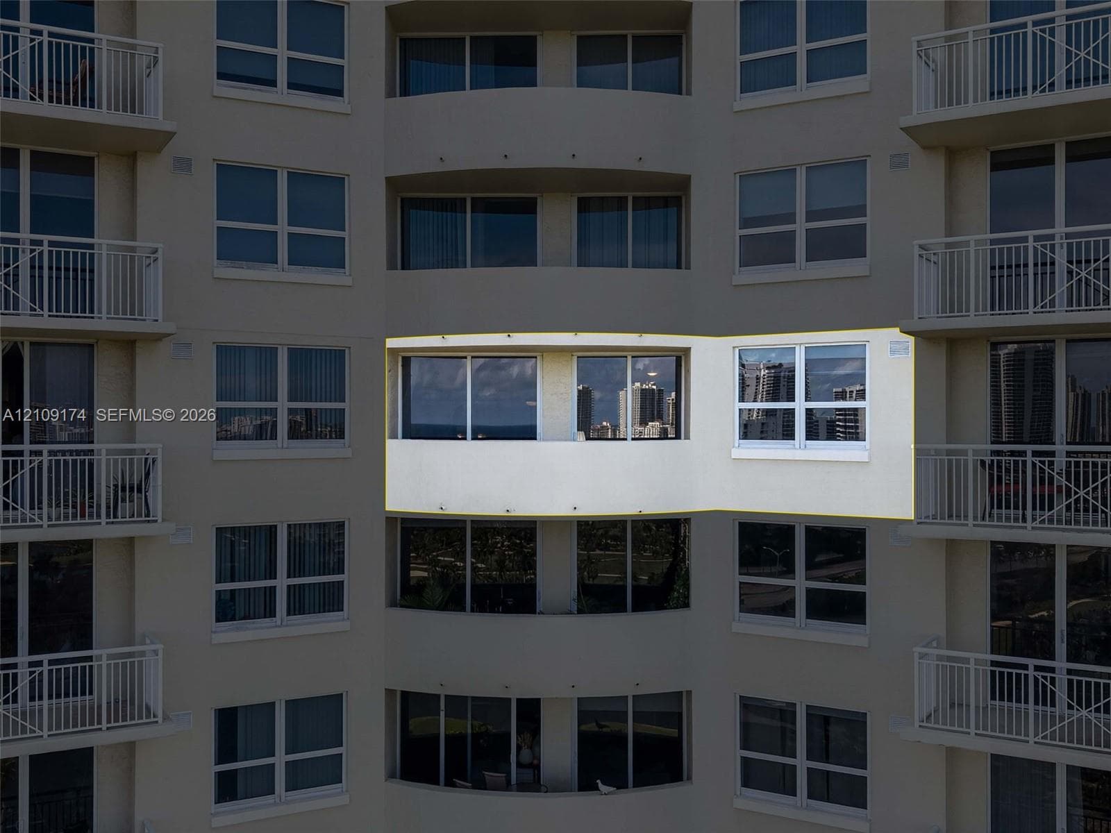 High-rise exterior featuring a recessed private balcony with glass sliding doors and dual-pane windows