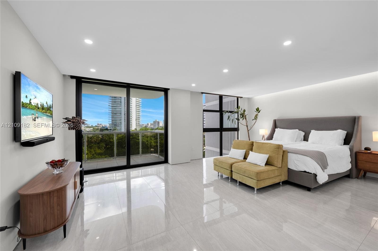 Spacious room featuring floor-to-ceiling glass sliding doors, polished tile flooring, recessed lighting, and a private balcony with glass railing