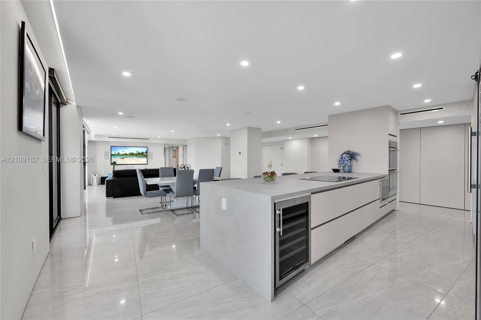 Modern kitchen featuring large format tile flooring, flat-panel cabinetry, a central island with a built-in wine refrigerator, and recessed lighting