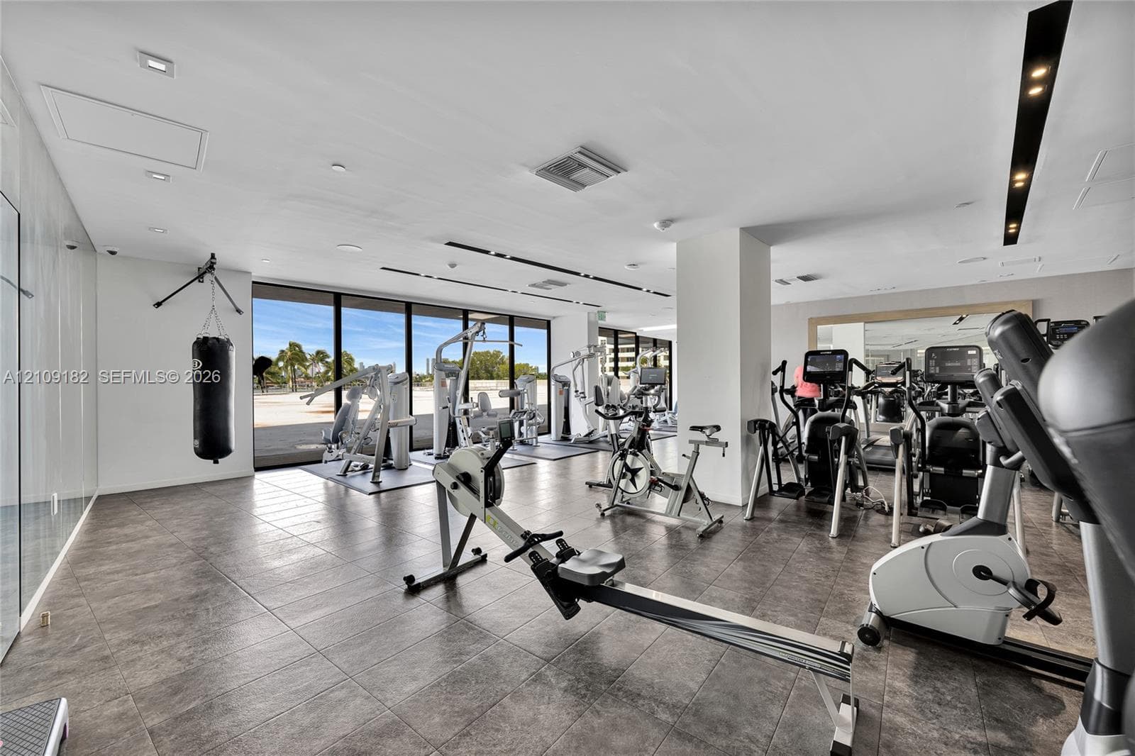 Fitness center featuring large-format tile flooring, floor-to-ceiling windows, recessed lighting, and wall-mounted mirrors