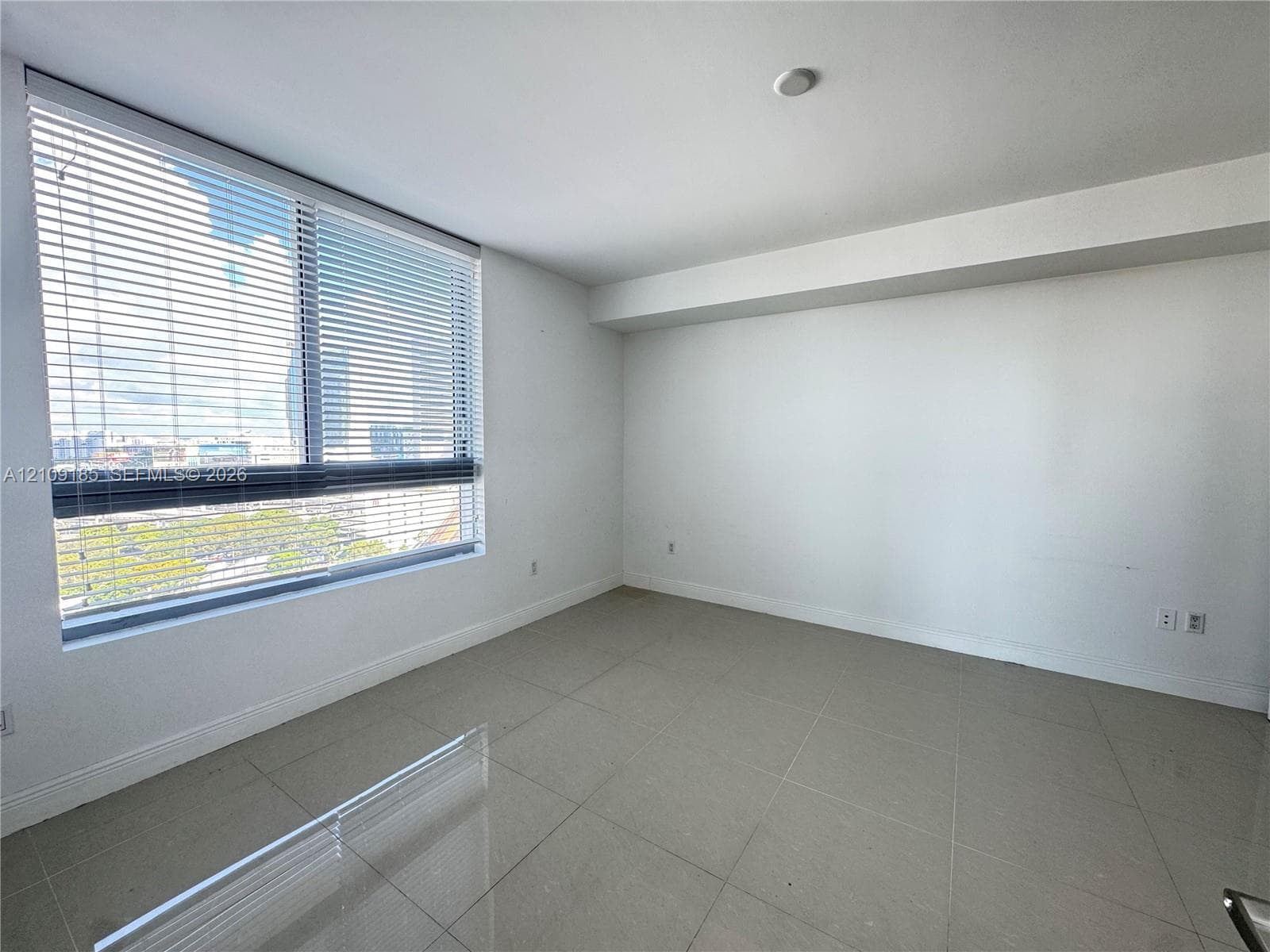 Interior space featuring large-format neutral floor tile, expansive floor-to-ceiling windows, and fitted horizontal blinds