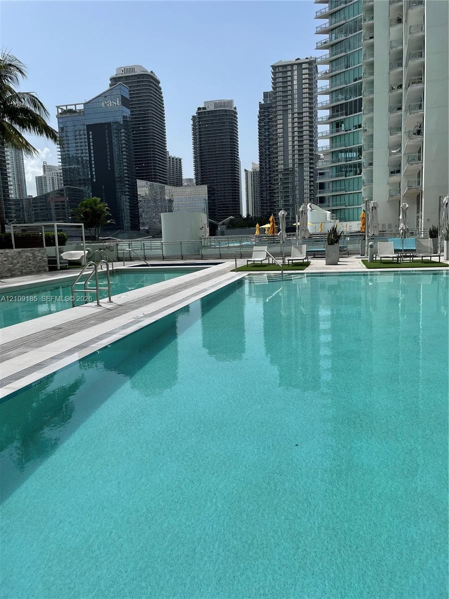 Swimming pool featuring a stone-tile deck, metal perimeter railings, and integrated step entry