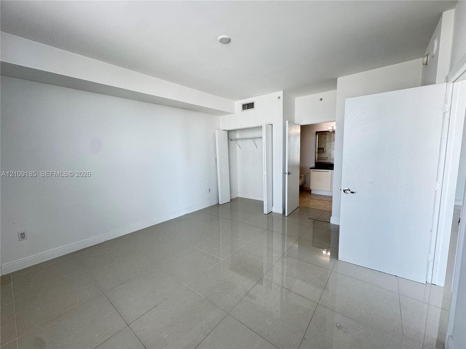 Neutral-toned tile flooring, built-in closet with shelving, and solid-core interior doors