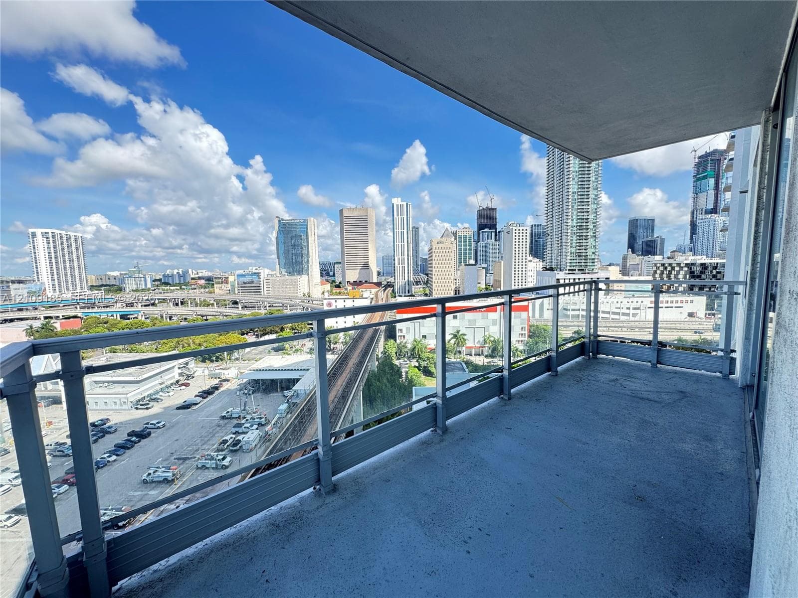 Covered outdoor balcony featuring a concrete floor and metal railing with glass panels