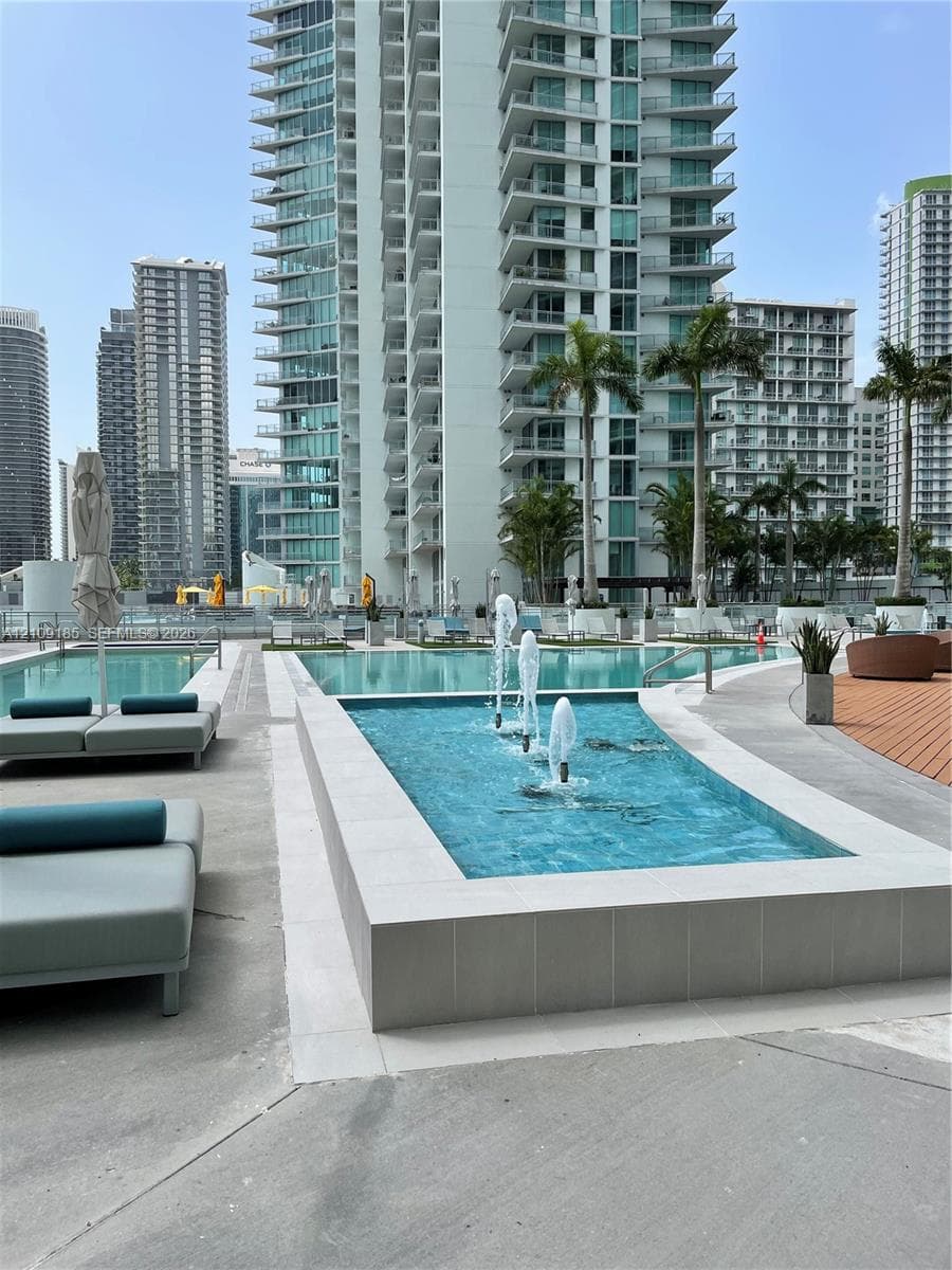 Swimming pool area featuring a rectangular fountain, concrete decking, and mature palm trees