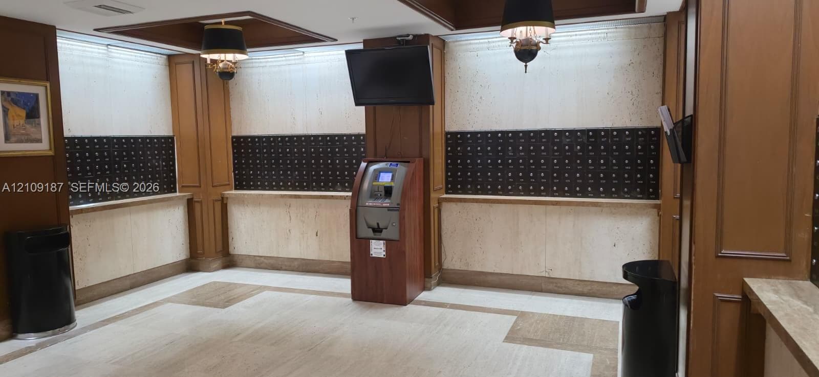 Mailboxes area featuring stone wall paneling, full-height wood millwork, pendant lighting, marble flooring and convenient ATM.