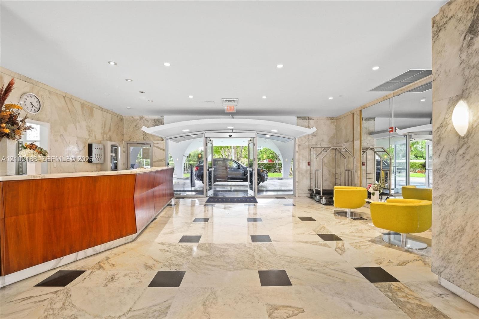 Lobby featuring stone tile flooring with decorative inlay, floor-to-ceiling multi-panel windows, wood-paneled walls, and recessed lighting