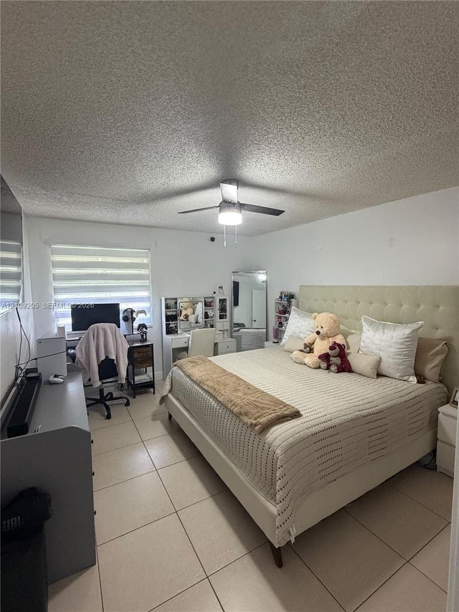 Room featuring large-format ceramic tile flooring, a ceiling fan with integrated lighting, and a multi-tiered window shade