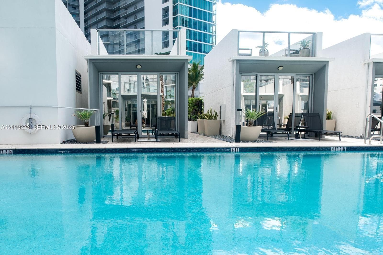 Swimming pool with stone paver decking, full-height glass sliding doors, and private elevated glass-railed balconies
