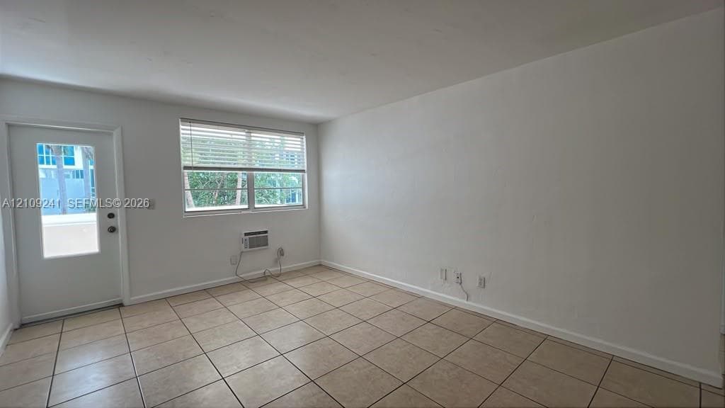 Interior room featuring ceramic tile flooring, a glass-panel entry door, and a horizontal window with adjustable blinds