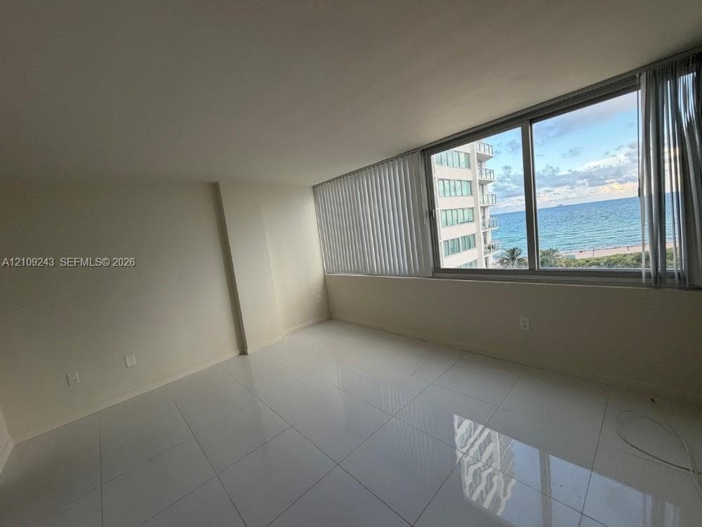 Large-format tile flooring, expansive window wall, and ocean horizon backdrop