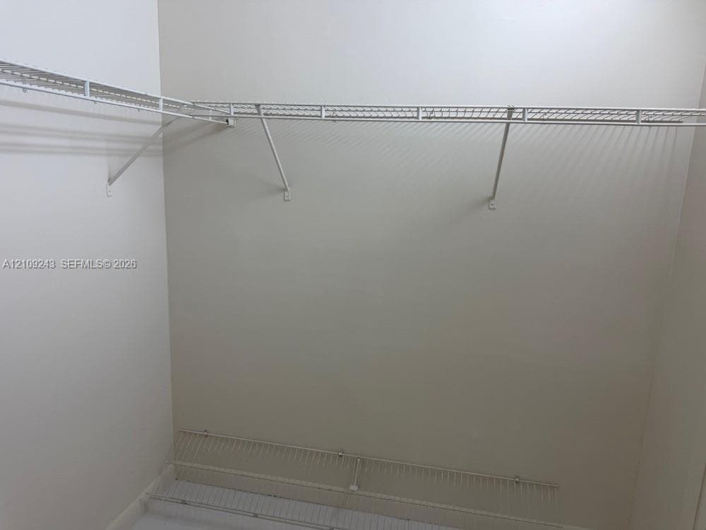 Storage area featuring dual-tier white wire shelving units mounted to painted walls
