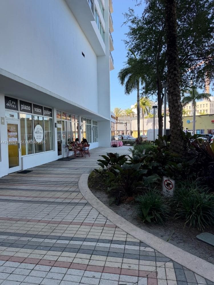 Ground-level commercial storefront featuring expansive glass pane windows, high-contrast exterior facade, and multi-tone paver walkway with integrated landscaping