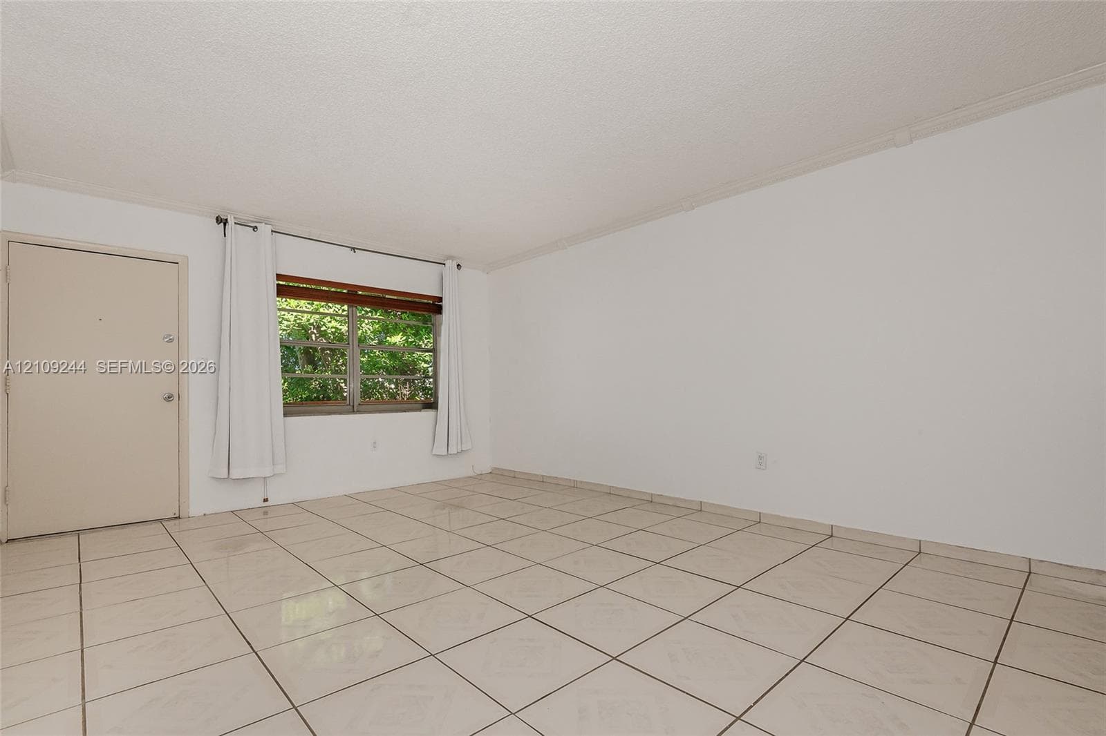 Interior space featuring large-format ceramic tile flooring, neutral walls, and a multi-pane window with wood-finish blinds