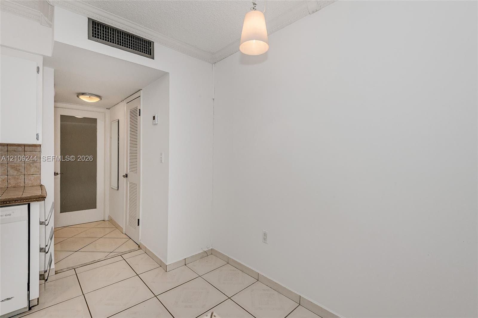 Ceramic tile flooring, crown molding, a hanging pendant light fixture, and interior door with a frosted glass panel