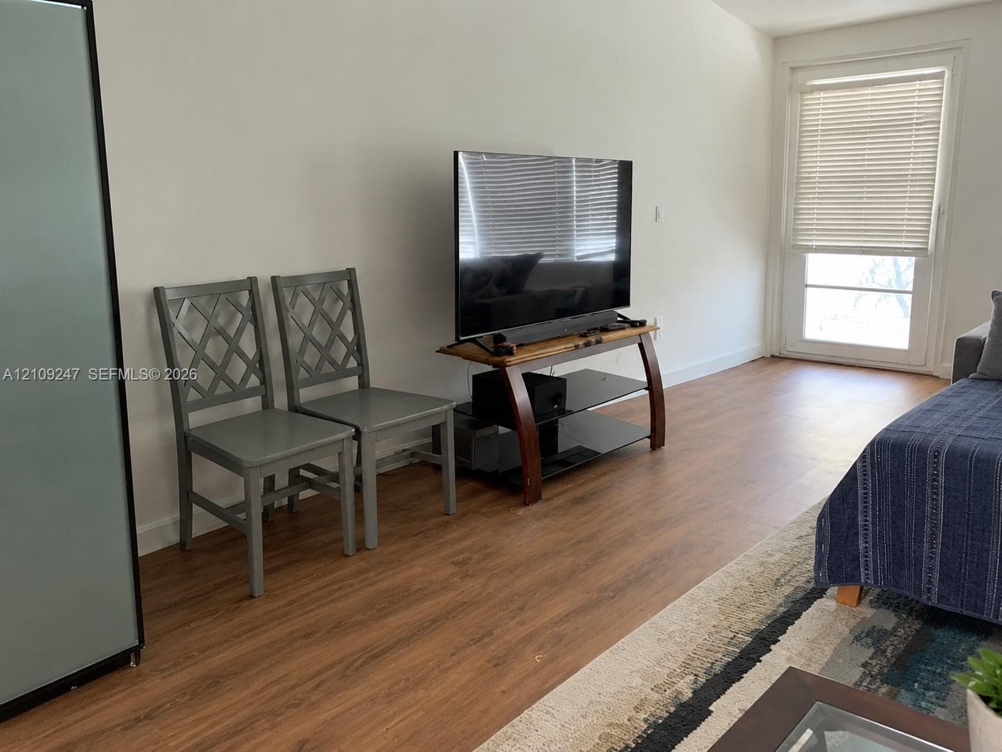 Wood-finish flooring, neutral walls, and a glass-paneled door featuring integrated blinds