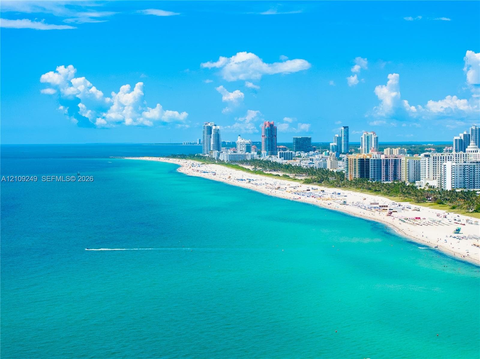 Aerial perspective of an expansive sandy coastline featuring turquoise ocean waters and an extensive metropolitan skyline