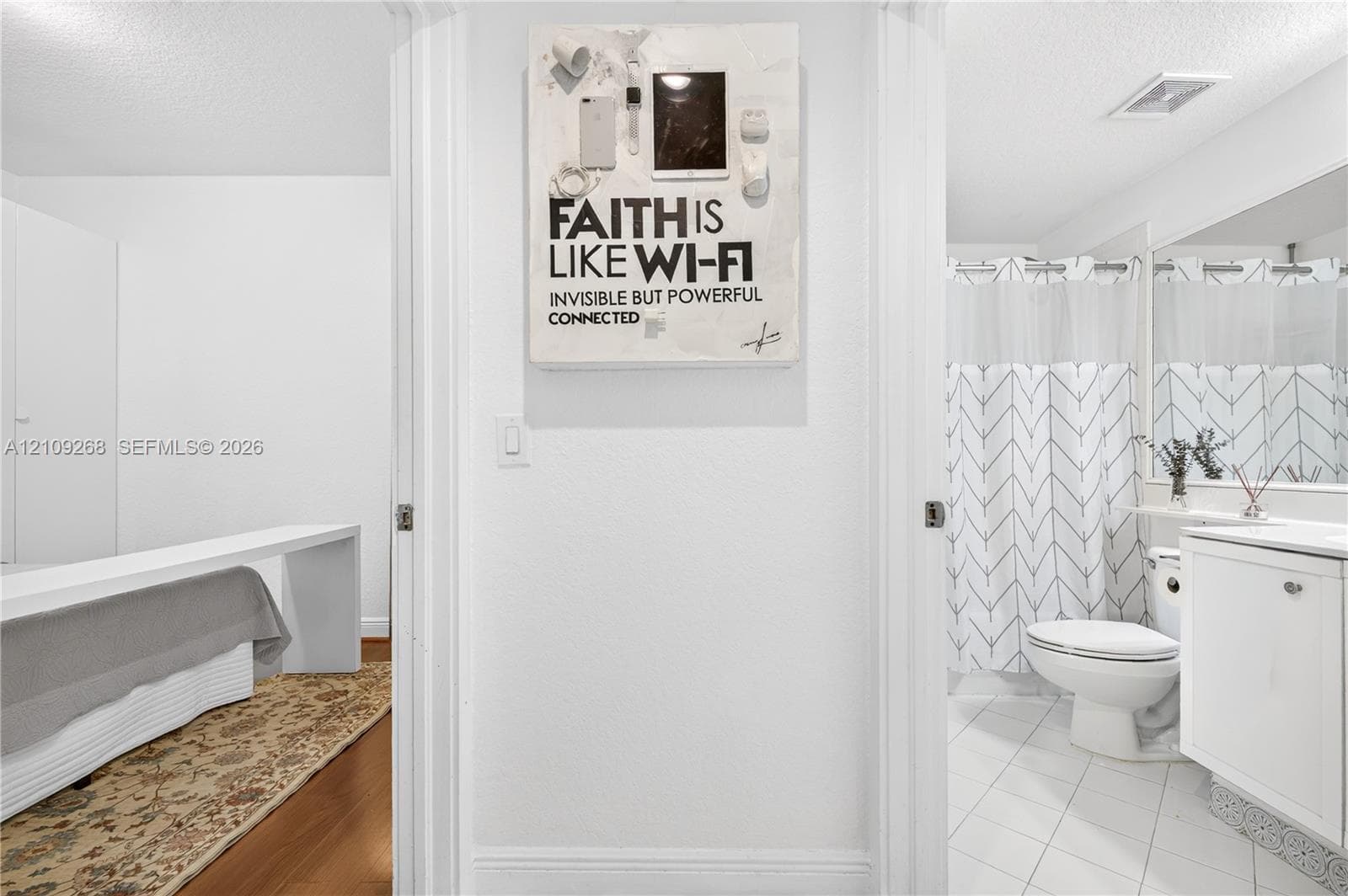 Bathroom featuring a white vanity cabinet, ceramic tile flooring, and a shower-tub combination with a wall-mounted mirror