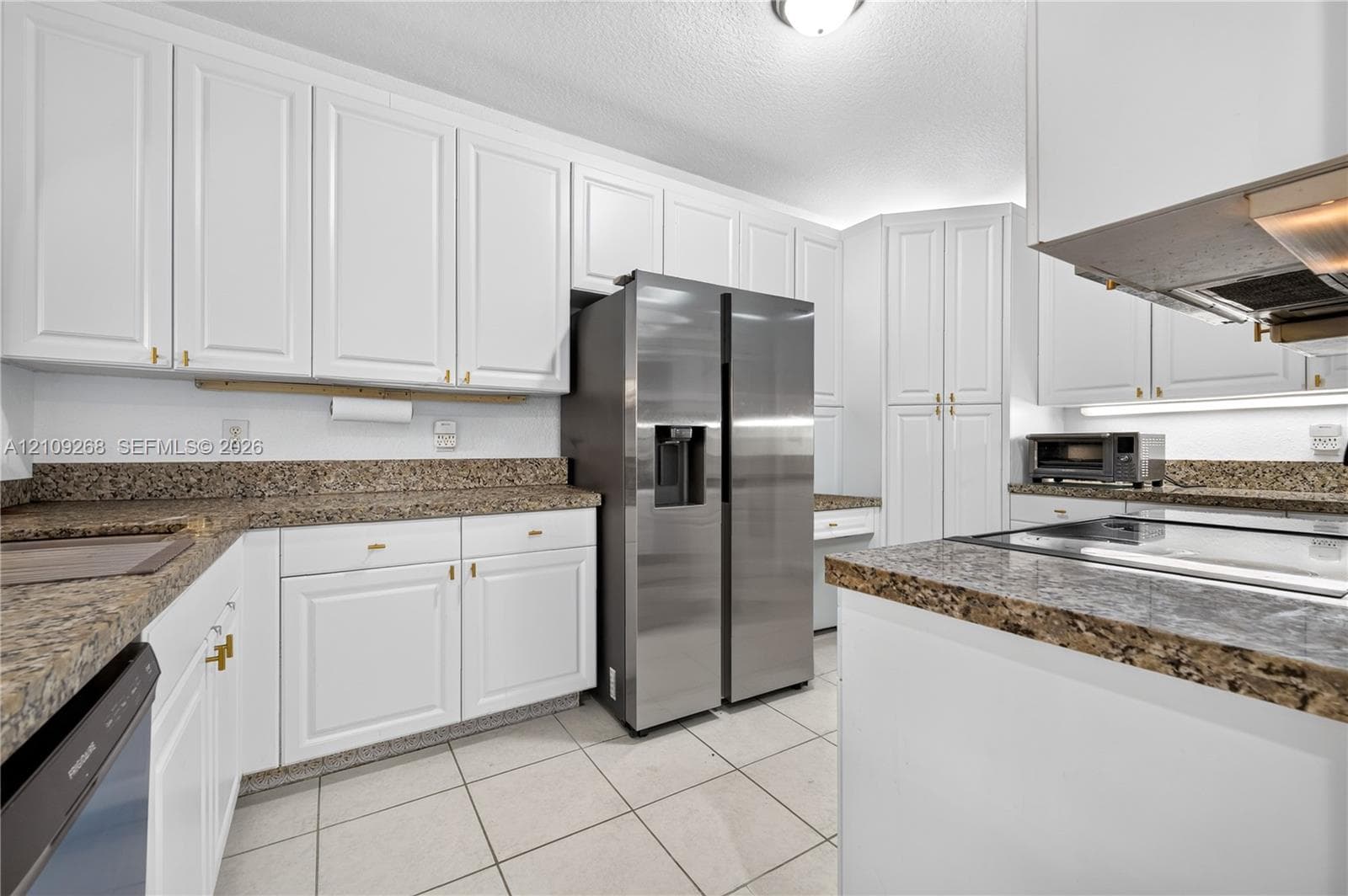 Kitchen featuring white cabinetry, stone-surface countertops, tile flooring, and stainless steel appliances