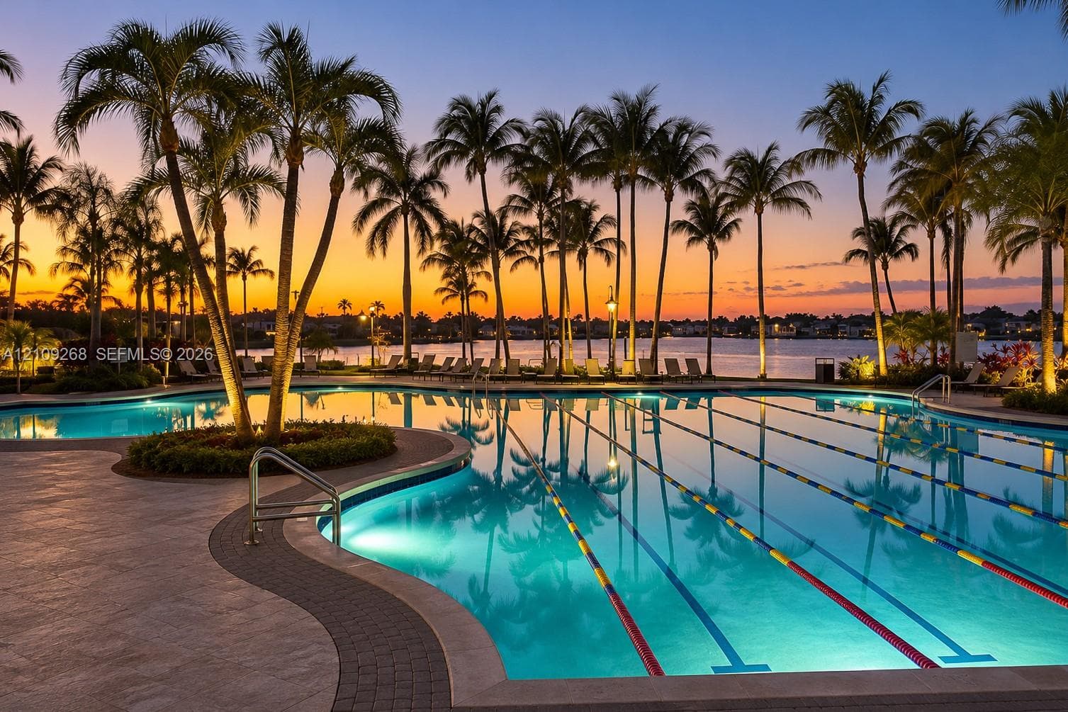 Swimming pool featuring lap lanes, a concrete deck, and palm tree landscaping overlooking the water