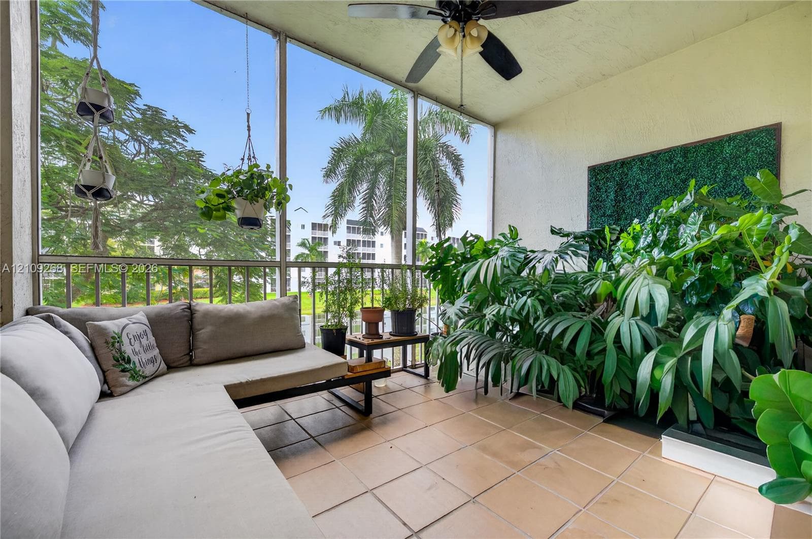 Screened-in balcony featuring tile flooring, metal railing, and a ceiling fan with integrated lighting