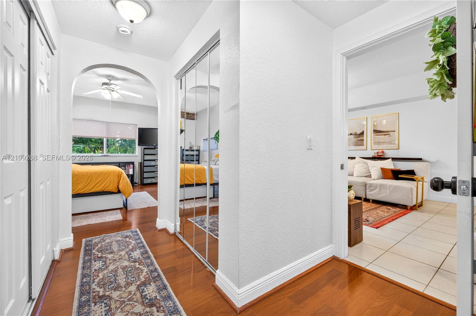 Hallway featuring wood-finish flooring, a built-in mirrored sliding-door closet, and an arched entryway