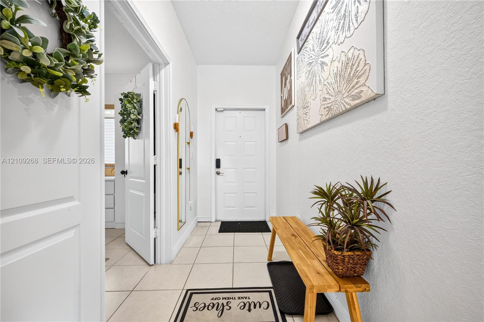 Neutral-tone ceramic tile flooring, solid-panel interior doors, and a multi-panel exterior entry door featuring a smart-lock deadbolt