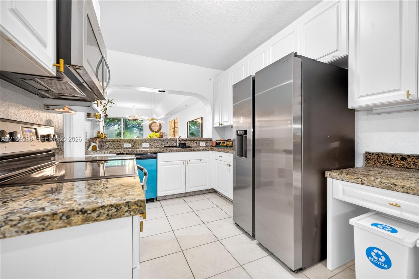 Kitchen featuring white cabinetry, stone countertops, tile flooring, and stainless steel appliances