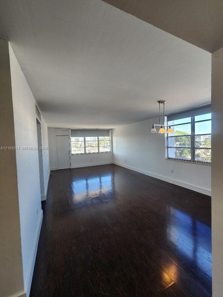 Open-concept room featuring dark wood-finish flooring, multi-pane windows, and a three-light pendant fixture
