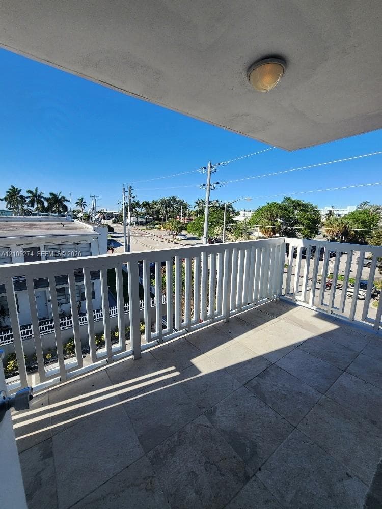 Private balcony featuring large-format tile flooring, white vertical railing, and ceiling-mounted lighting
