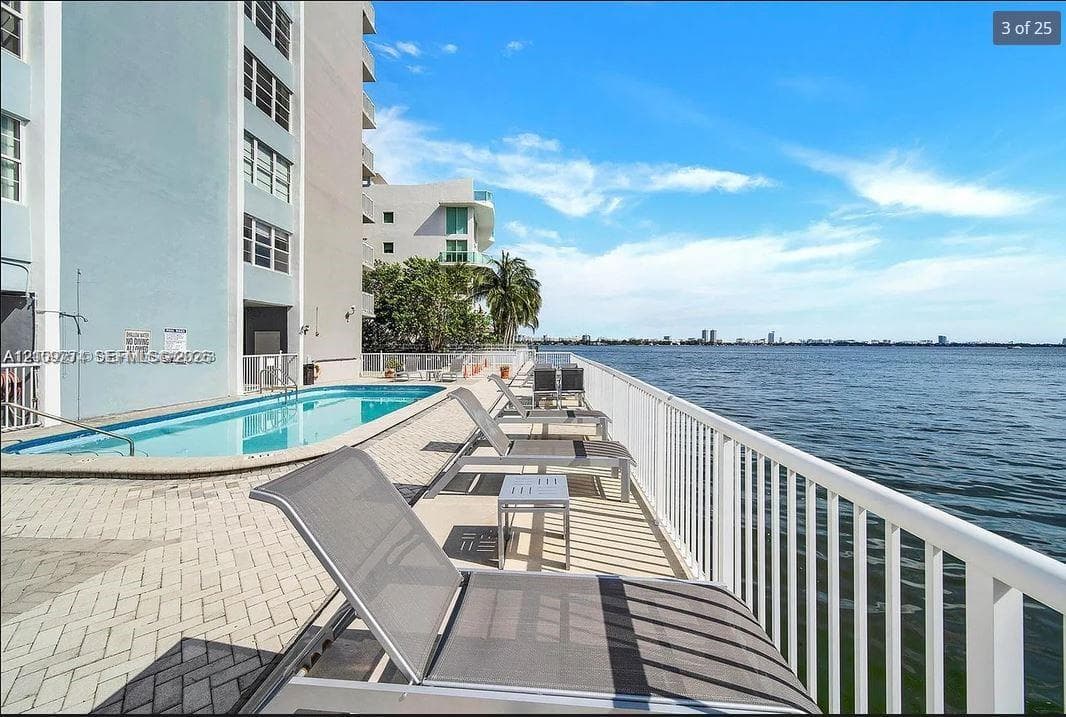 Waterfront swimming pool area featuring paver decking, a metal perimeter railing, and direct water exposure