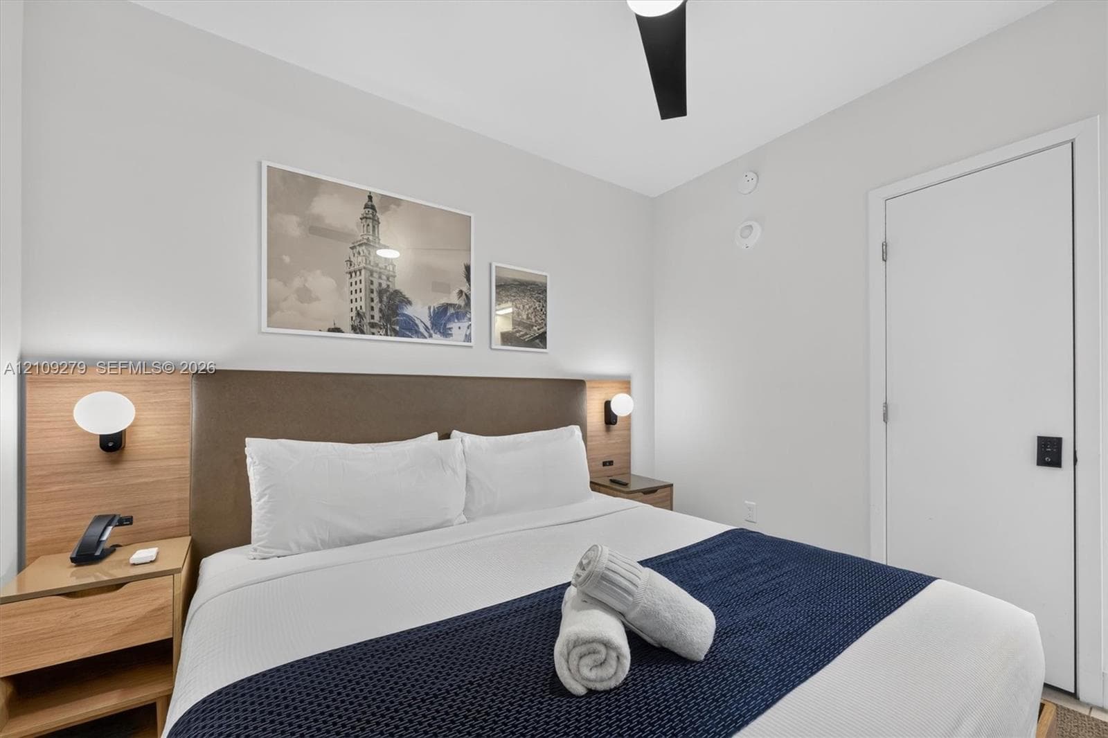 Built-in wood-finish headboard with integrated side tables, wall-mounted globe lighting, and matte black hardware