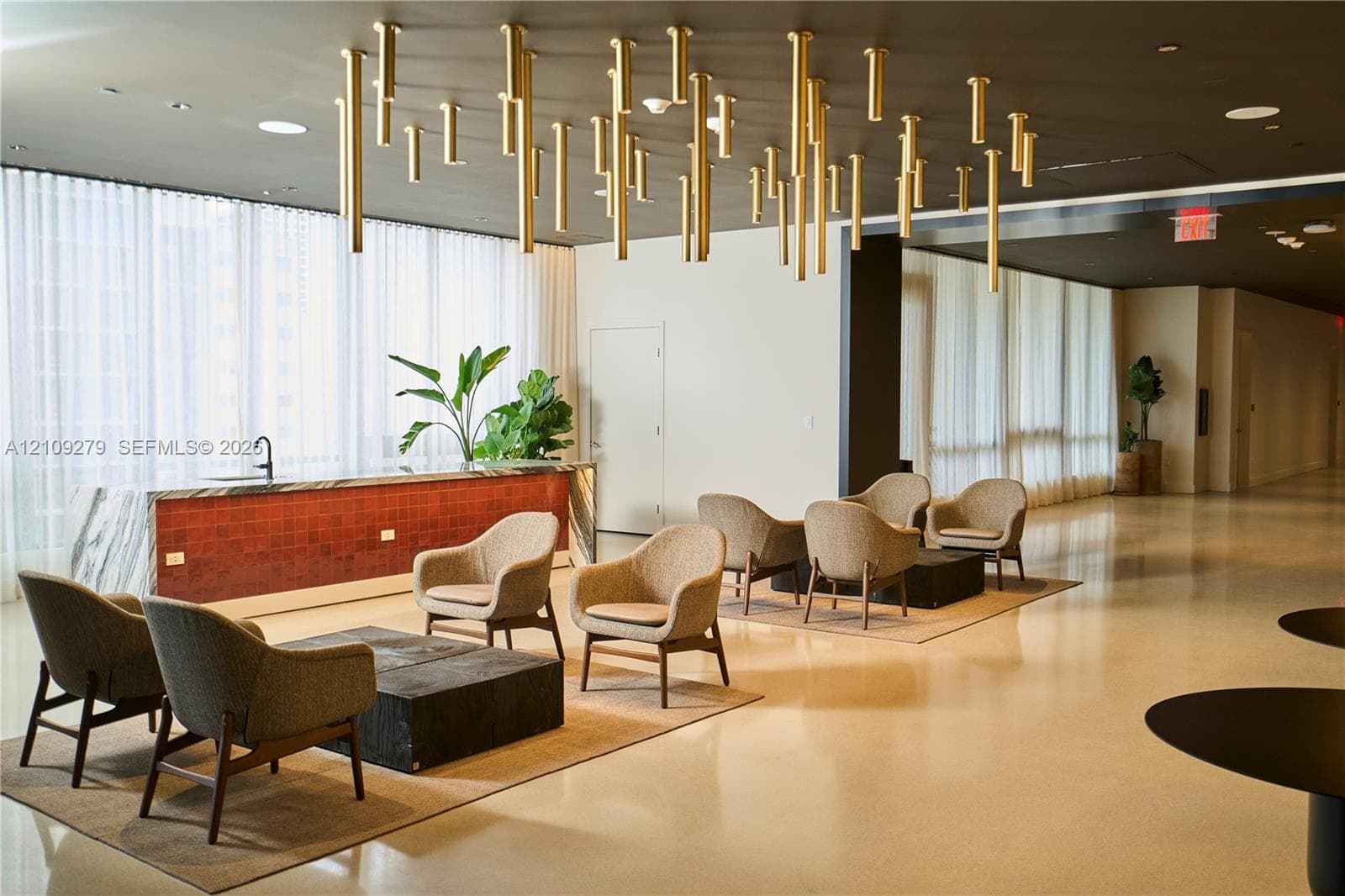 Common area featuring polished stone flooring, floor-to-ceiling sheer window treatments, a built-in counter with a tiled base, and a contemporary ceiling-mounted geometric light installation