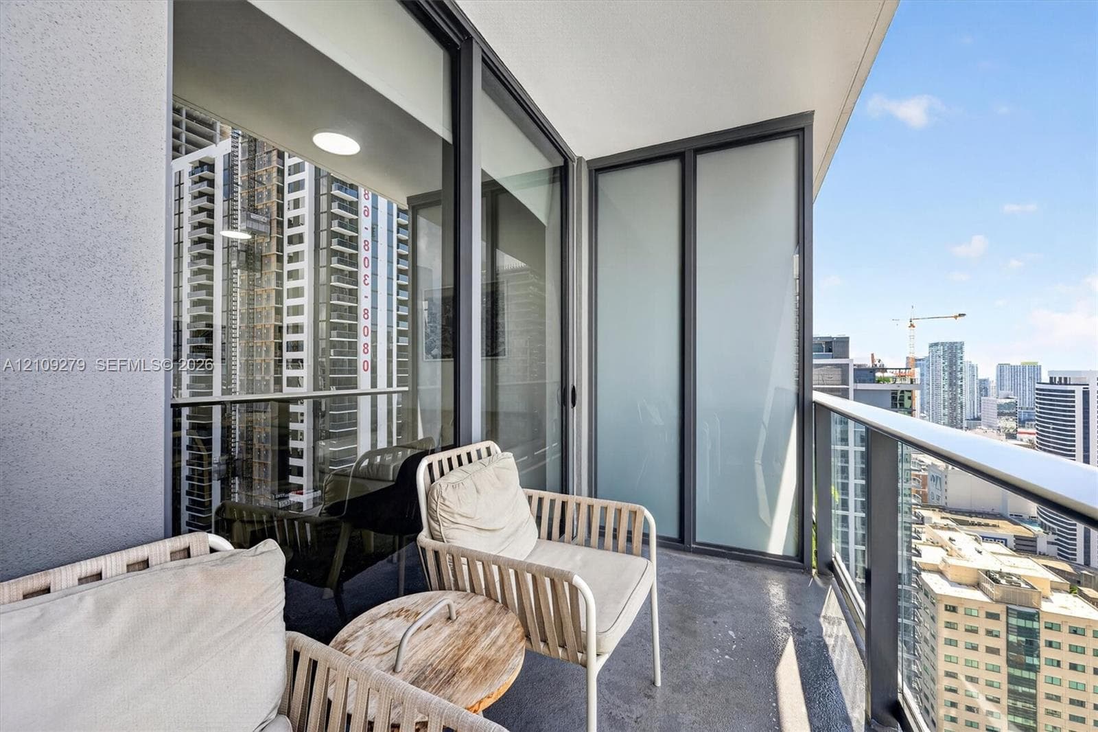 Covered balcony featuring a concrete floor, glass panel railing, and frosted privacy partitions