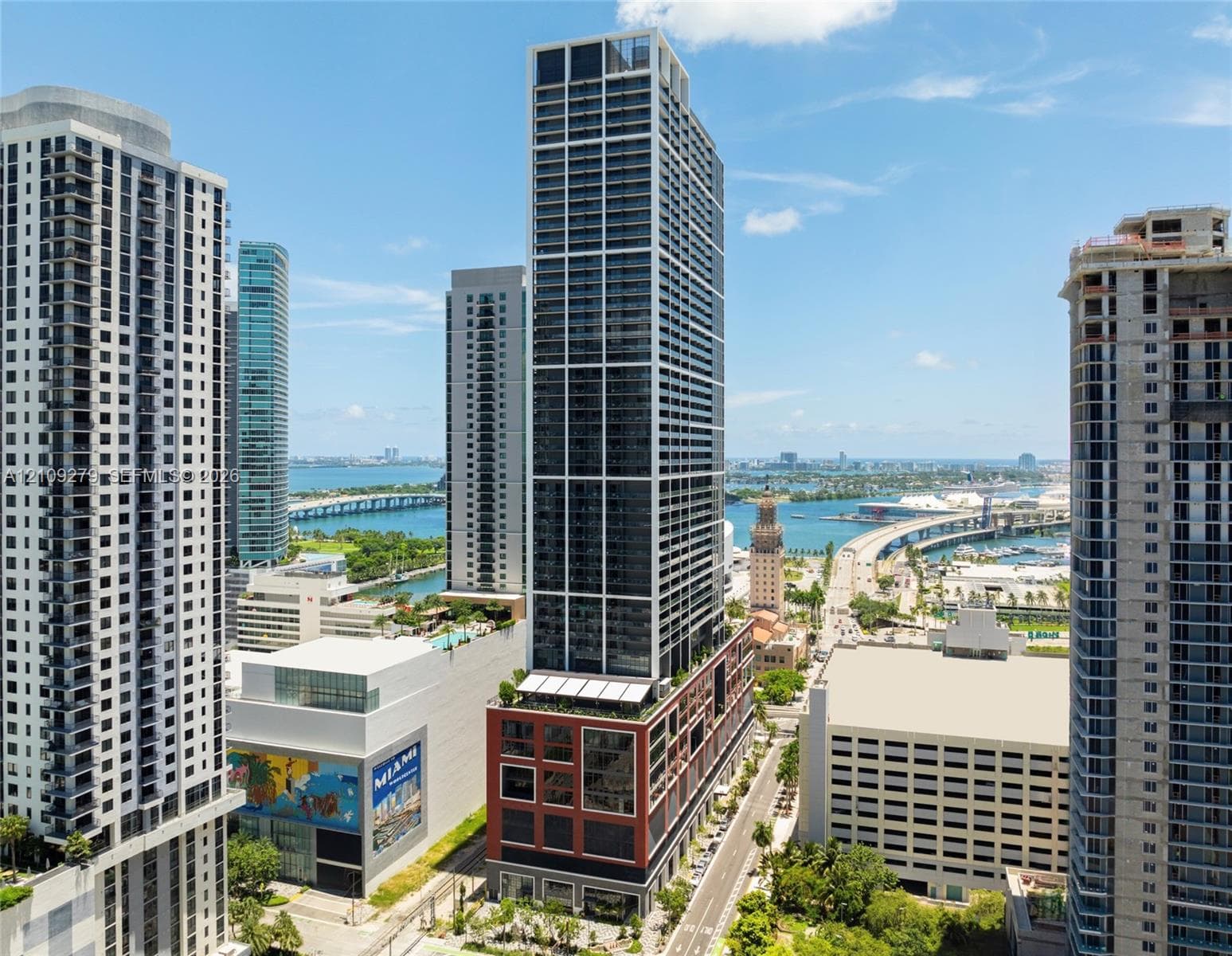 High-rise architectural structure featuring a grid-pattern glass facade, expansive floor-to-ceiling windows, and a multi-level podium base with integrated terrace spaces