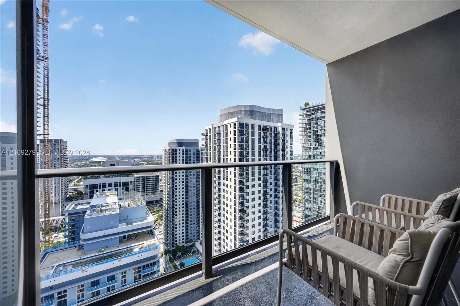 Private balcony featuring a glass-panel railing, dark-toned flooring, and high-rise urban surroundings
