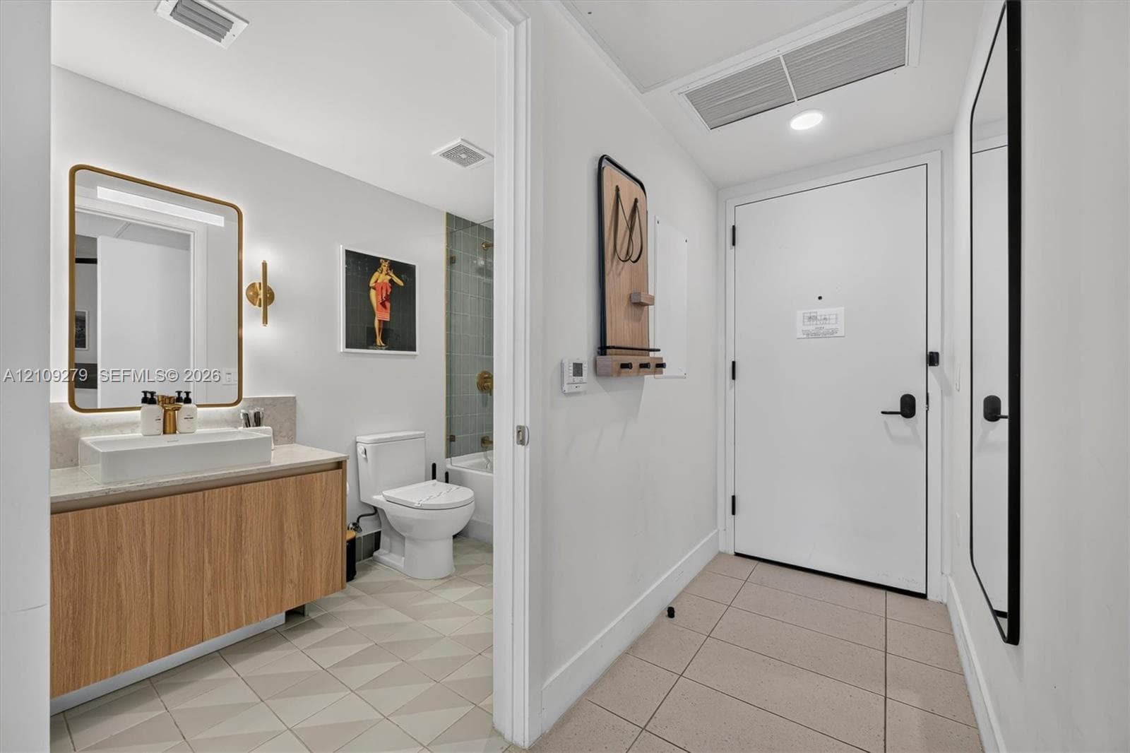 Bathroom featuring a floating vanity with wood-finish cabinetry, rectangular vessel sink, wall-mounted light fixture, and tile flooring