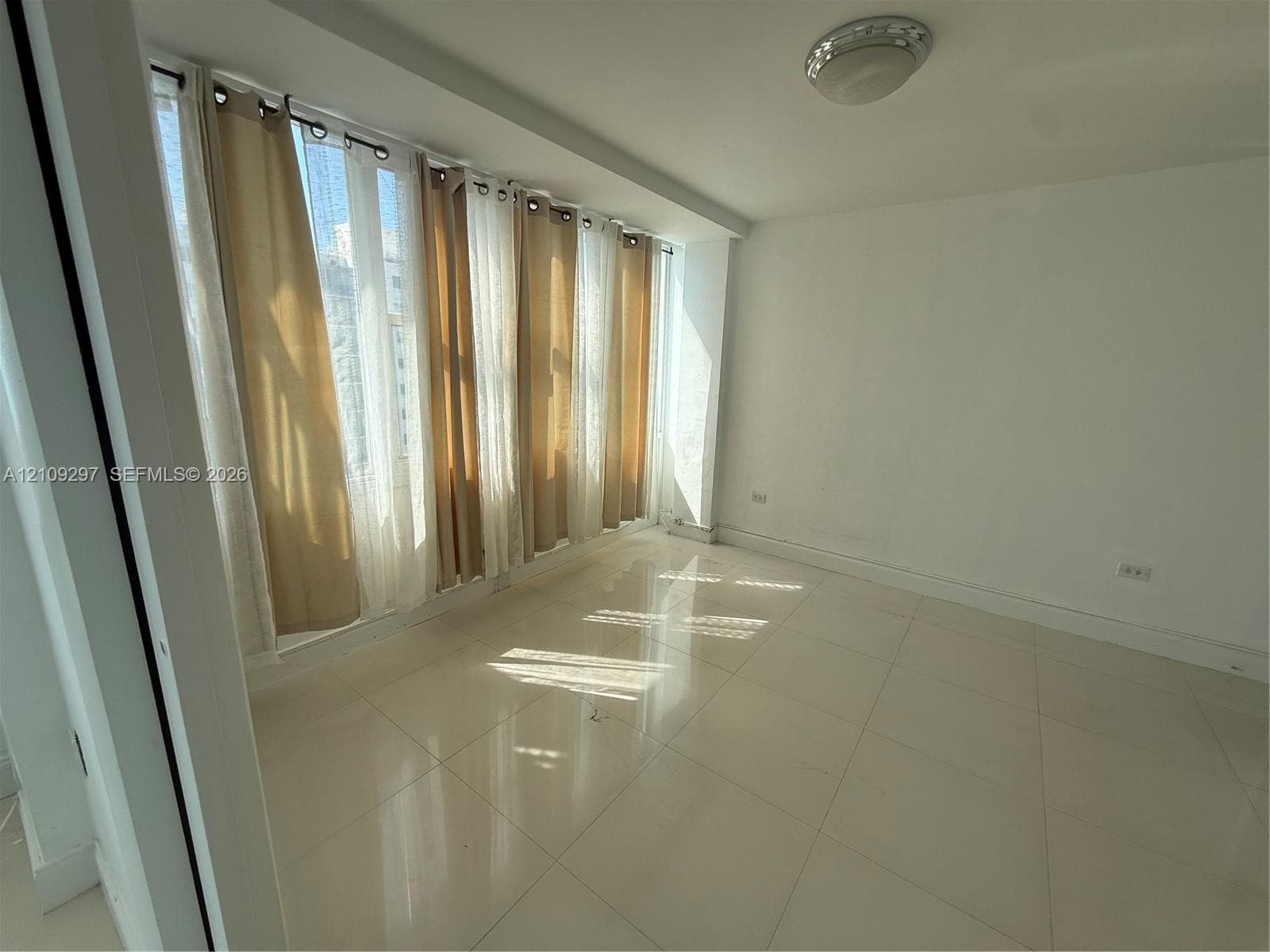 Large-format tile flooring, expansive floor-to-ceiling windows, and flush-mount overhead lighting