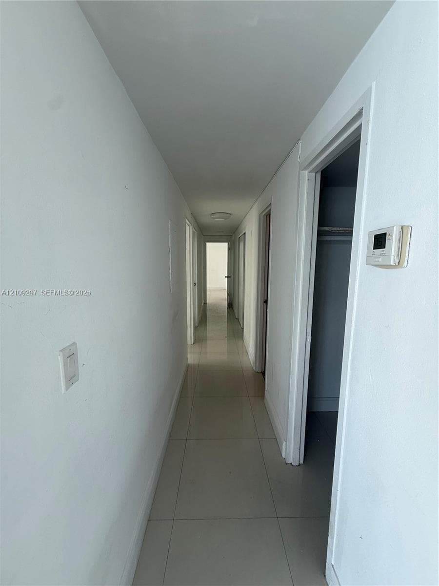 Neutral-toned tile flooring, flush-mount ceiling lighting, and multiple interior door openings