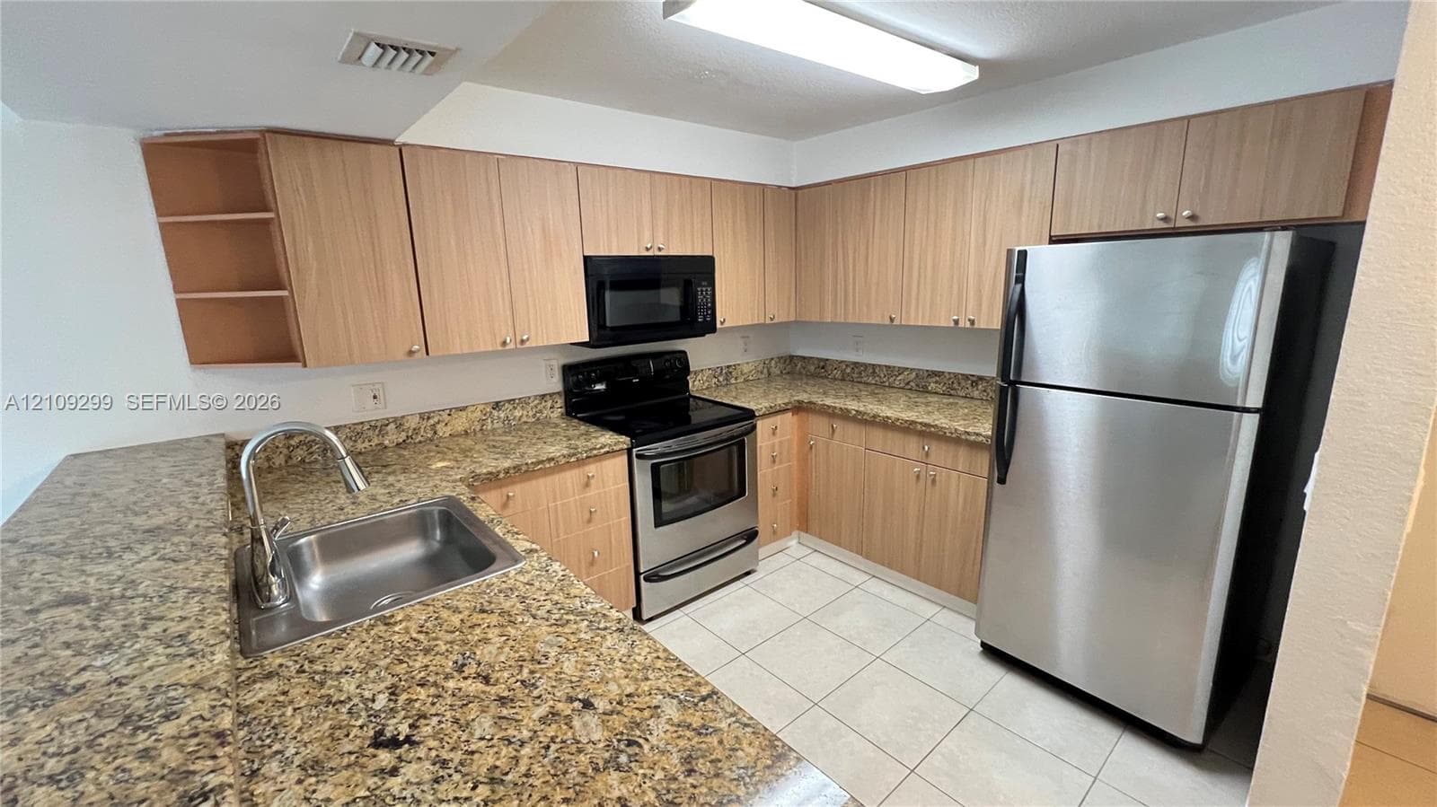 Kitchen featuring light-finish cabinetry, stone-surface countertops, stainless steel appliances, ceramic tile flooring, and a single-basin undermount sink with a high-arch faucet